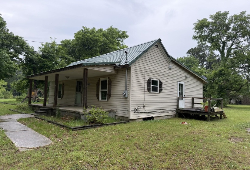 Cottage-style residence featuring a metal roof, siding exterior, and a covered front porch with four columns