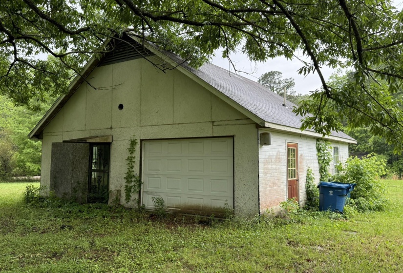 Detached structure featuring a single garage door, a side entry door, and a shingle roof