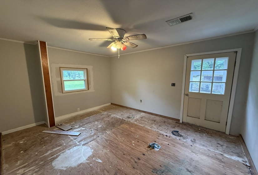 Interior space featuring light-colored walls, exposed subflooring, and a ceiling-mounted fan with integrated lighting