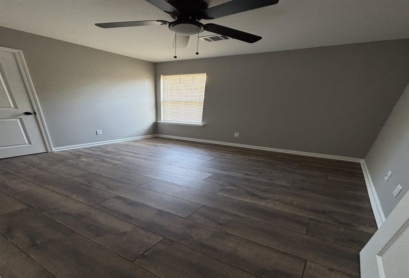 Bedroom featuring wood-finish flooring, neutral gray walls, a single window, white trim, and an overhead ceiling fan with light fixture