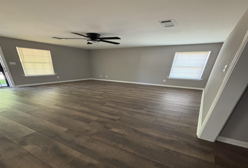 Spacious room featuring wood-finish flooring, neutral gray wall paint, and white baseboards
