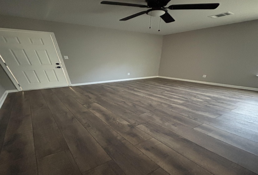 Spacious room featuring wood-finish flooring, light gray wall paint, and white baseboards
