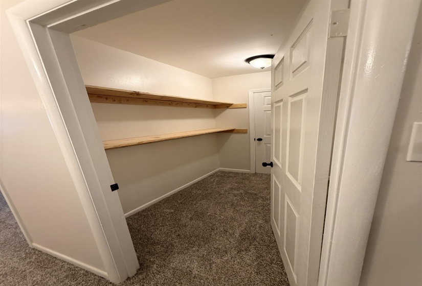 Interior storage closet featuring multiple wood shelves, neutral wall paint, and recessed lighting