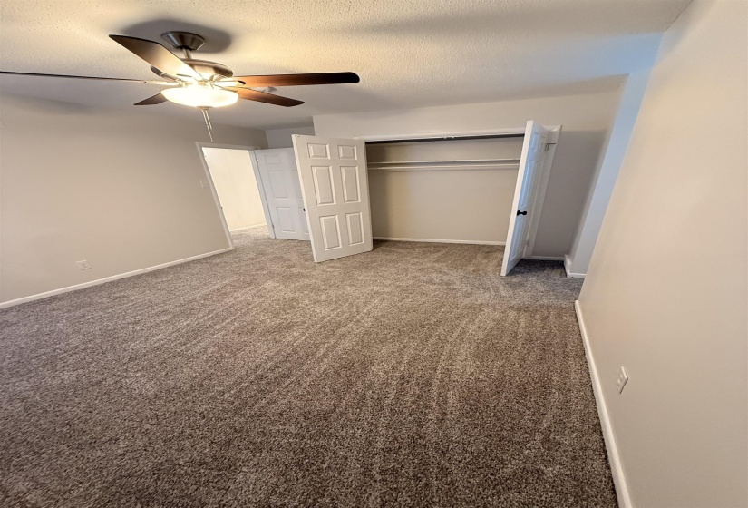 Carpeted interior room featuring neutral wall paint, white trim, and a ceiling fan with light fixture