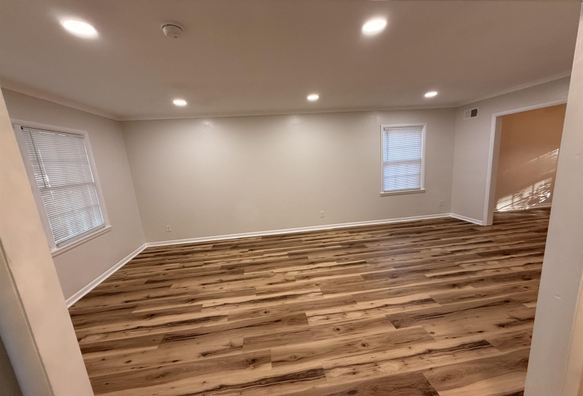 Open concept room featuring wood-finish flooring, two windows with blinds, recessed lighting, and crown molding