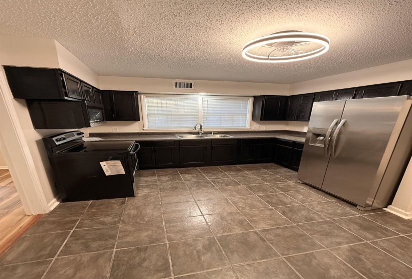 Kitchen featuring dark cabinetry, stainless steel refrigerator, and a built-in microwave