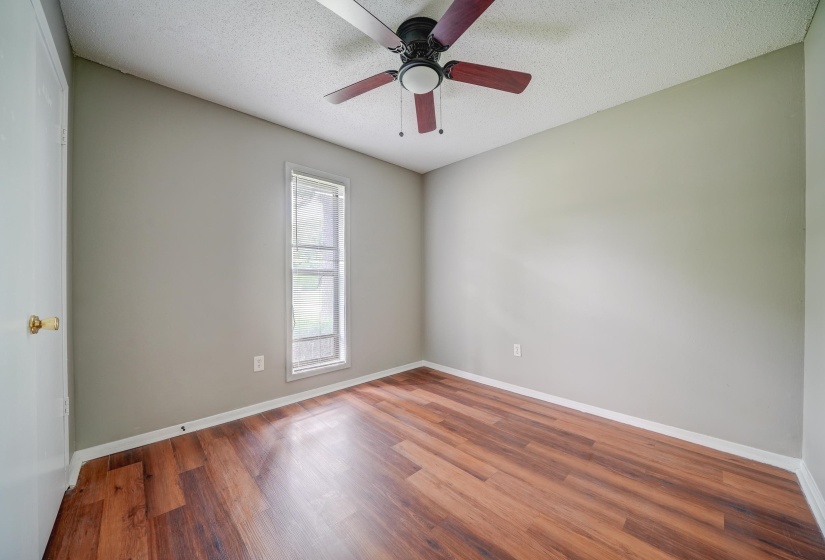 Empty room with a textured ceiling, wood finished floors, and ceiling fan