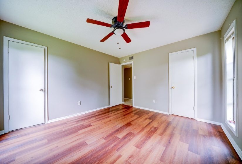 Unfurnished bedroom with light wood-style flooring, ceiling fan, and multiple closets