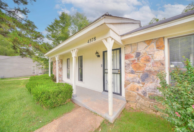Entrance to property with stone siding and covered porch