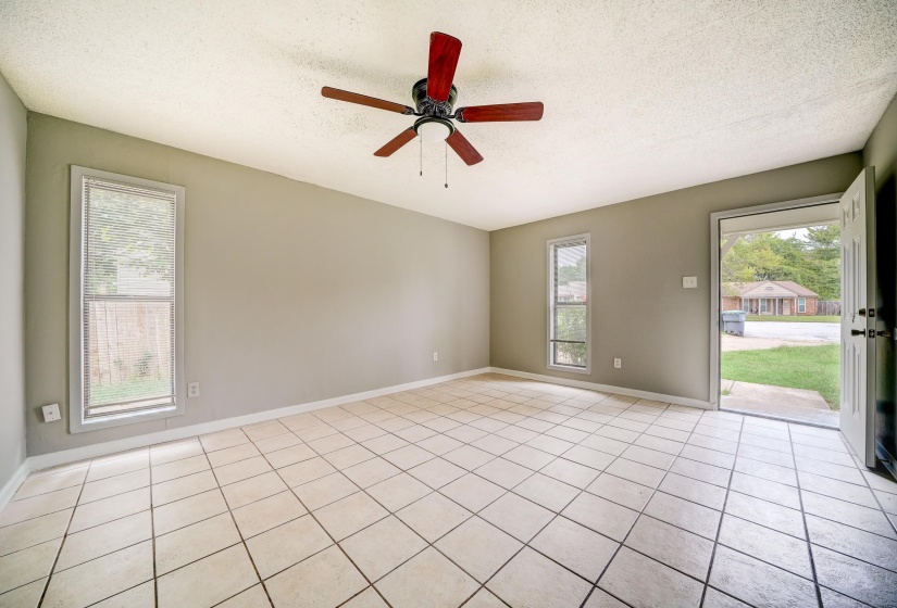Empty room with a textured ceiling, light tile patterned flooring, healthy amount of natural light, and a ceiling fan