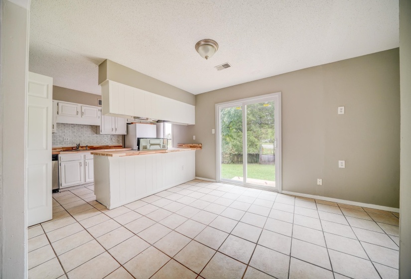 Kitchen with a peninsula, white cabinets, light tile patterned floors, a textured ceiling, and decorative backsplash