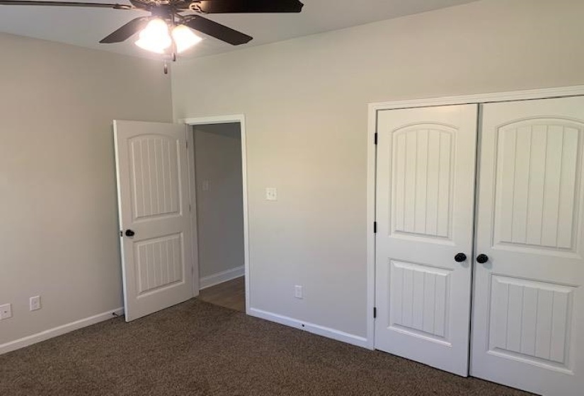 Unfurnished bedroom featuring baseboards, a closet, dark carpet, and a ceiling fan