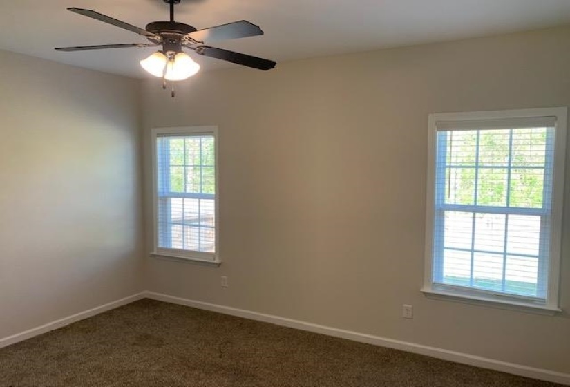 Empty room with dark carpet, baseboards, and ceiling fan