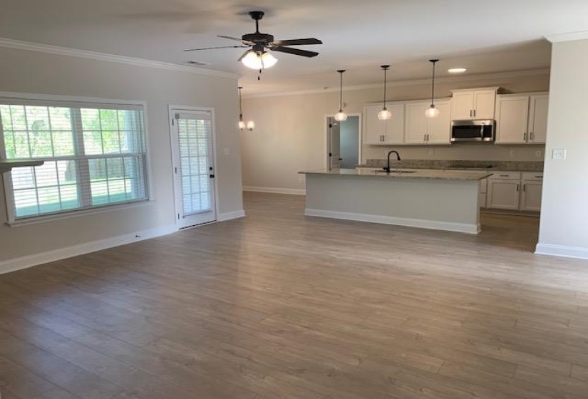 Kitchen featuring stainless steel microwave, ornamental molding, ceiling fan, a sink, and wood finished floors