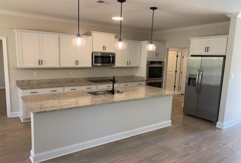 Kitchen with a sink, ornamental molding, appliances with stainless steel finishes, and white cabinetry