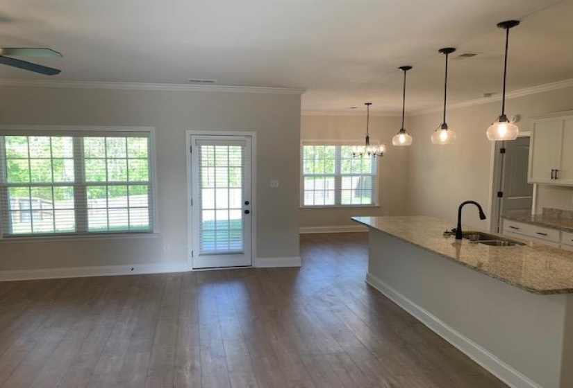 Kitchen with a sink, dark wood-style floors, crown molding, white cabinetry, and ceiling fan with notable chandelier