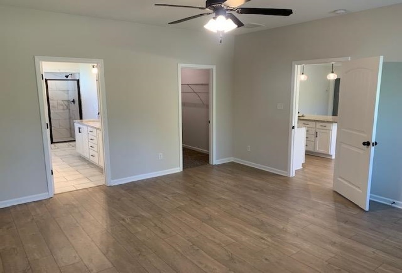 Unfurnished bedroom featuring a walk in closet, a closet, baseboards, and wood finished floors
