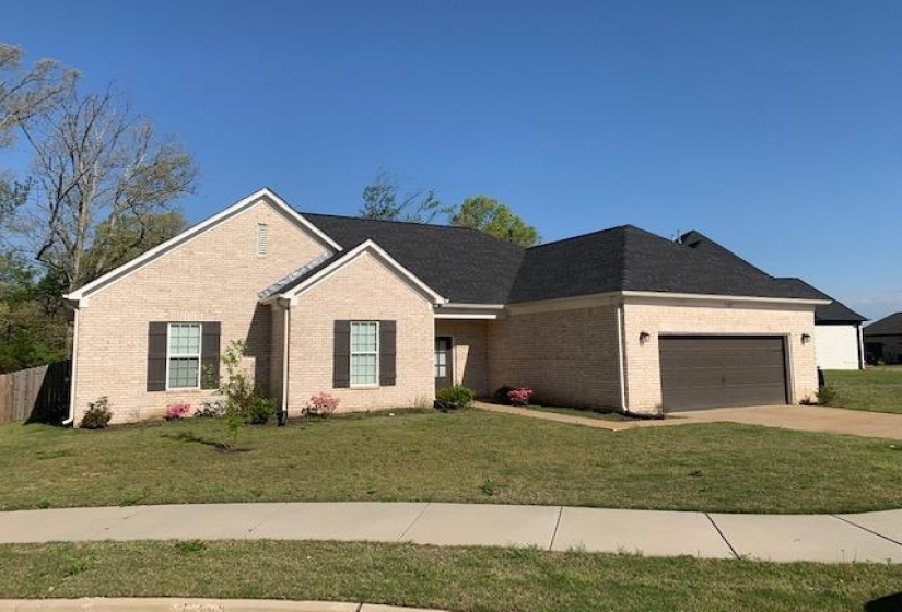 Ranch-style home with a front yard, brick siding, a garage, and concrete driveway