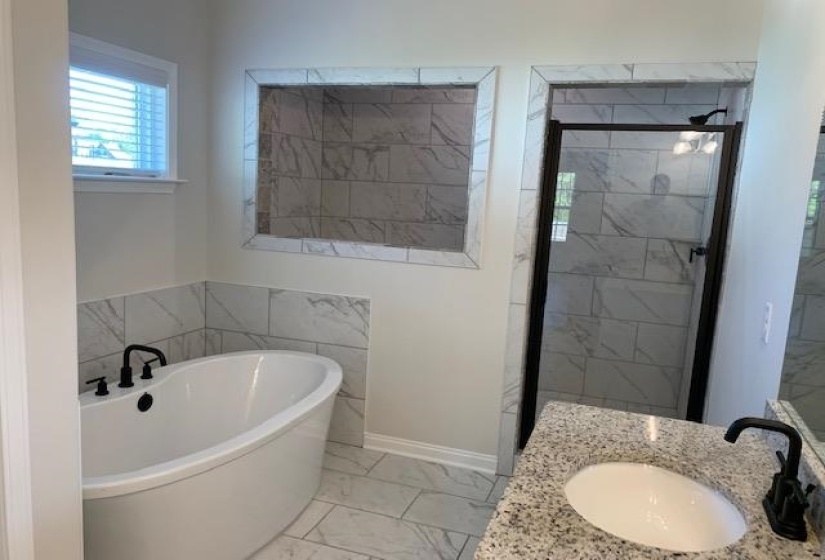 Bathroom featuring baseboards, a stall shower, a soaking tub, marble finish floor, and a sink