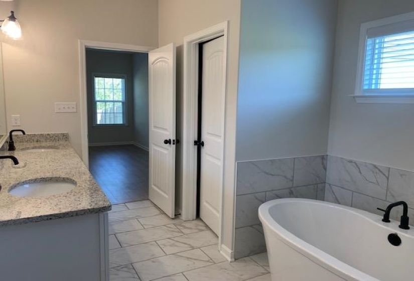 Bathroom featuring double vanity, marble finish floor, a sink, and a soaking tub