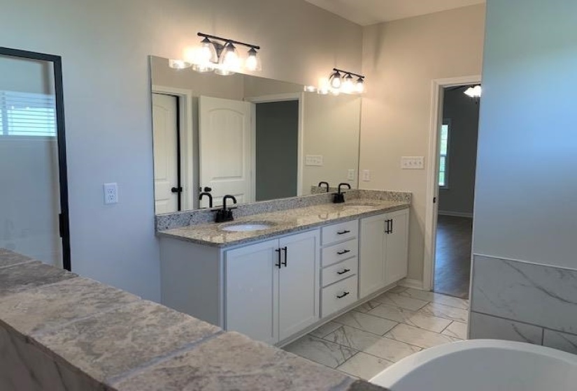 Bathroom with a freestanding tub, double vanity, marble finish floor, and a sink