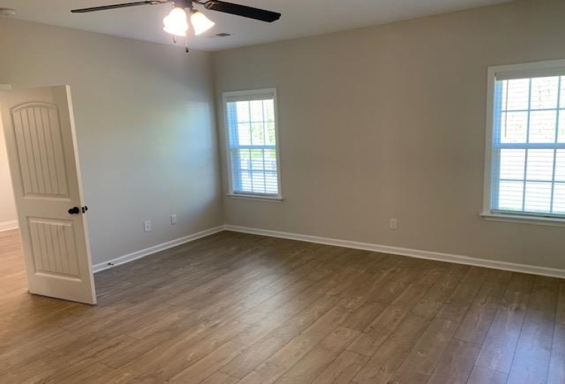 Empty room featuring a healthy amount of sunlight, a ceiling fan, and wood finished floors