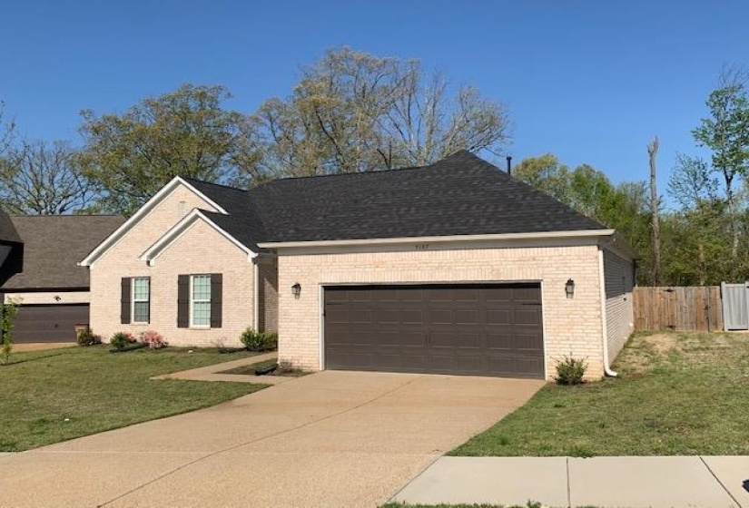 View of front facade with concrete driveway, a front lawn, brick siding, a garage, and fence
