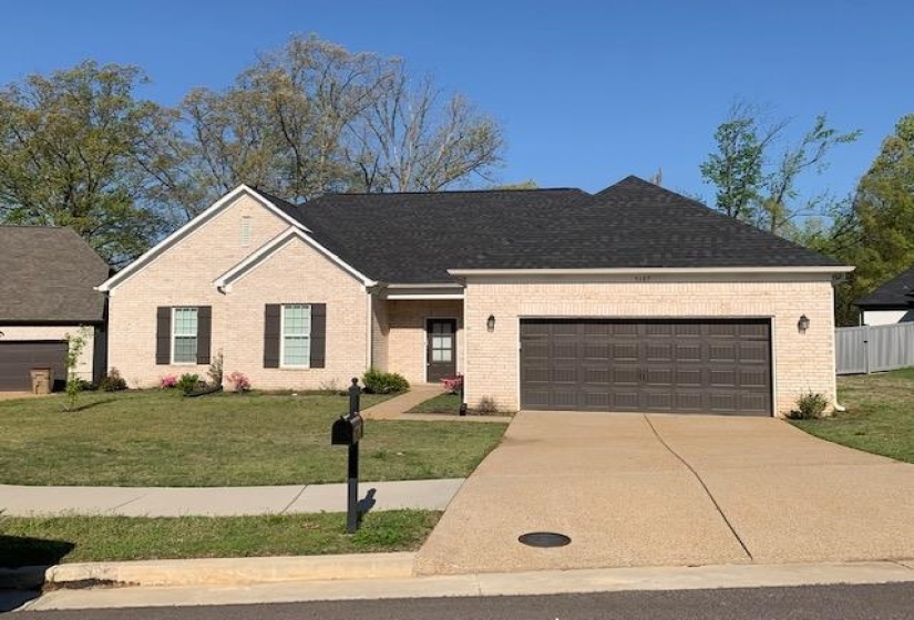 Ranch-style house with a front yard, brick siding, driveway, and an attached garage