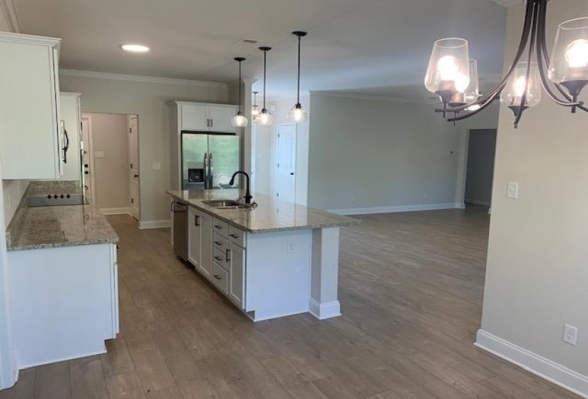 Kitchen with a notable chandelier, baseboards, ornamental molding, stainless steel fridge, and a sink