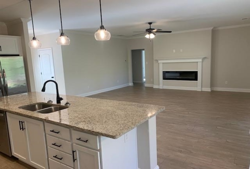 Kitchen with an island with sink, ornamental molding, a ceiling fan, white cabinets, and a sink