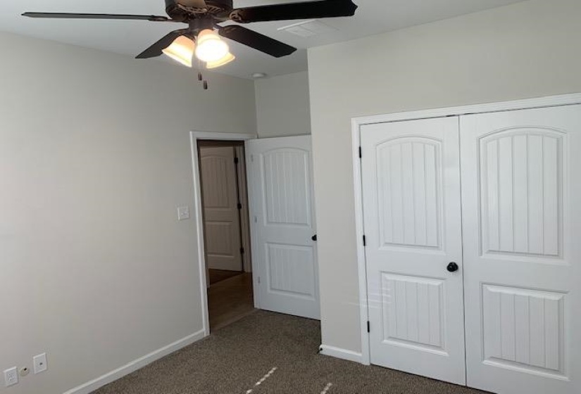 Unfurnished bedroom with dark carpet, baseboards, a closet, and ceiling fan
