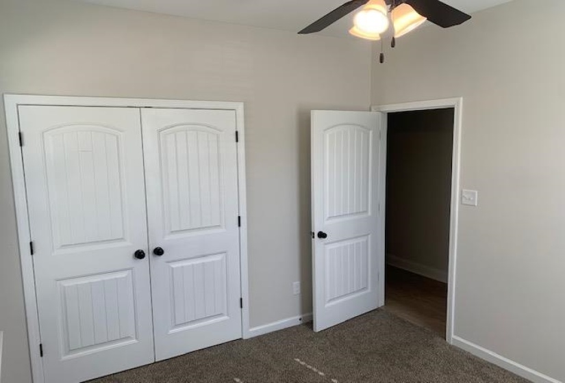 Unfurnished bedroom with a closet, carpet, baseboards, and a ceiling fan