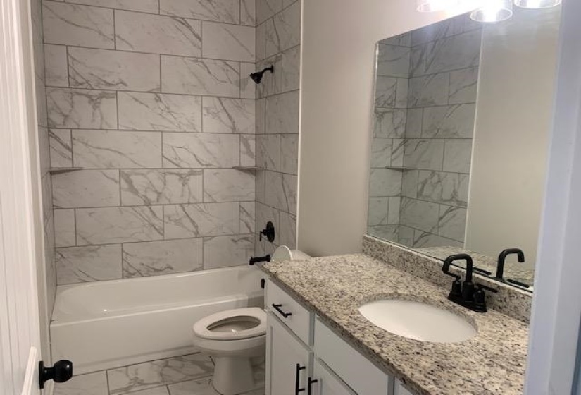 Bathroom with vanity, marble finish floor, toilet, and tub / shower combination