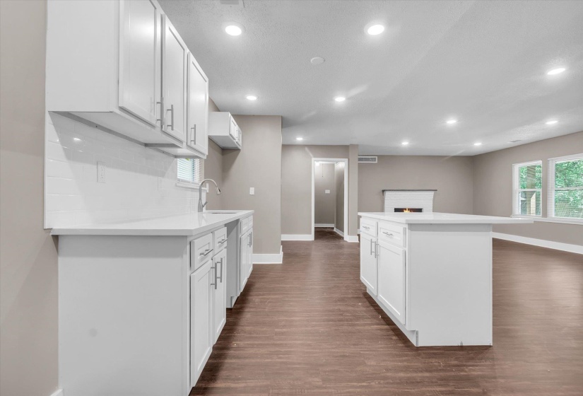 Modern kitchen featuring white shaker cabinetry, white subway tile backsplash, white countertops, a center island, and wood-finish flooring