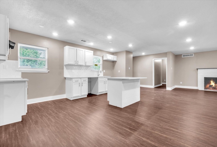 Open-concept kitchen and living area featuring wood-finish flooring, recessed lighting, and a white kitchen island