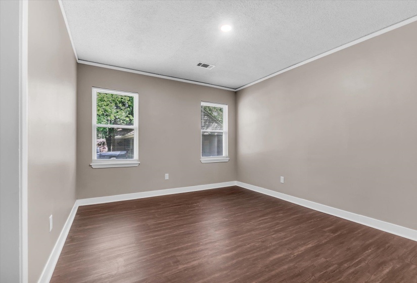 Room featuring wood-finish flooring, two windows, recessed ceiling lighting, crown molding, and neutral wall paint
