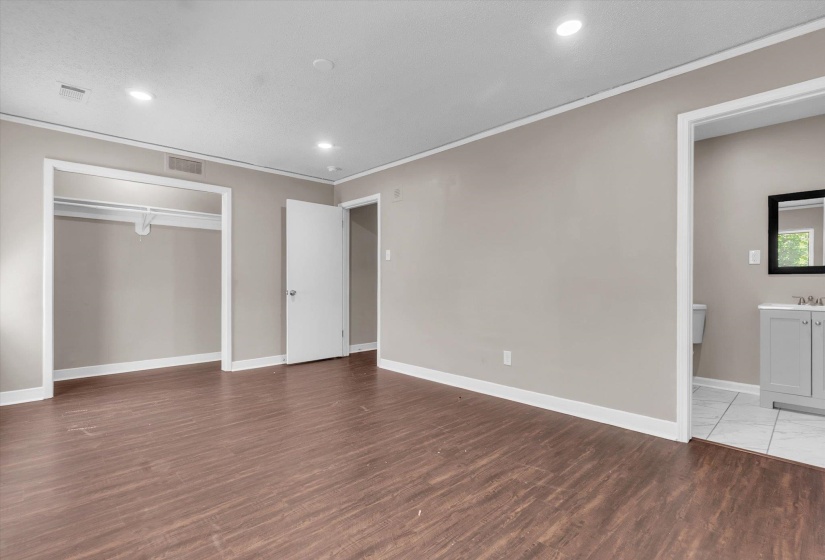 Spacious interior room with wood-finish flooring, recessed lighting, and light neutral wall paint