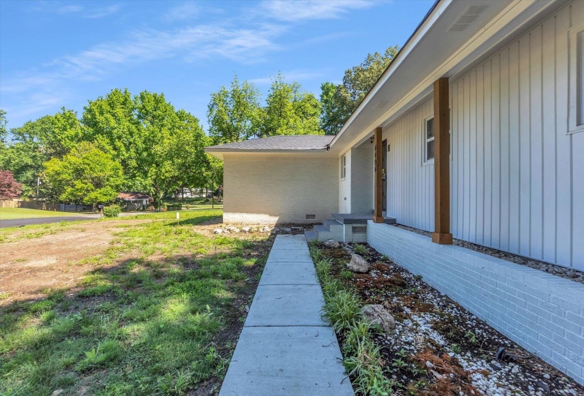Modernized ranch exterior featuring vertical white siding, natural wood-tone support columns, and a light gray brick foundation