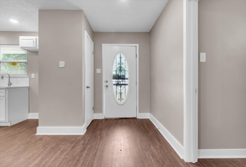 Entry foyer featuring wood-finish flooring and a white door with decorative glass inlay