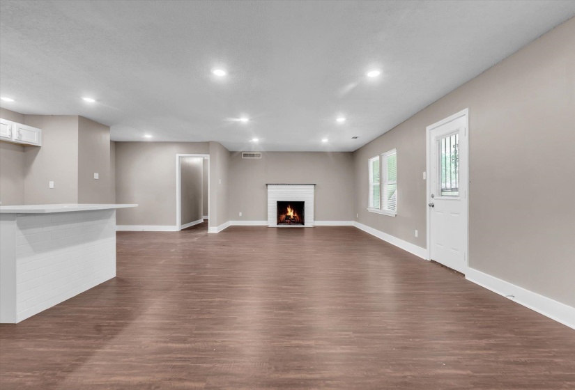 Spacious living area featuring wood-finish flooring, recessed lighting, and a white fireplace with a mantel