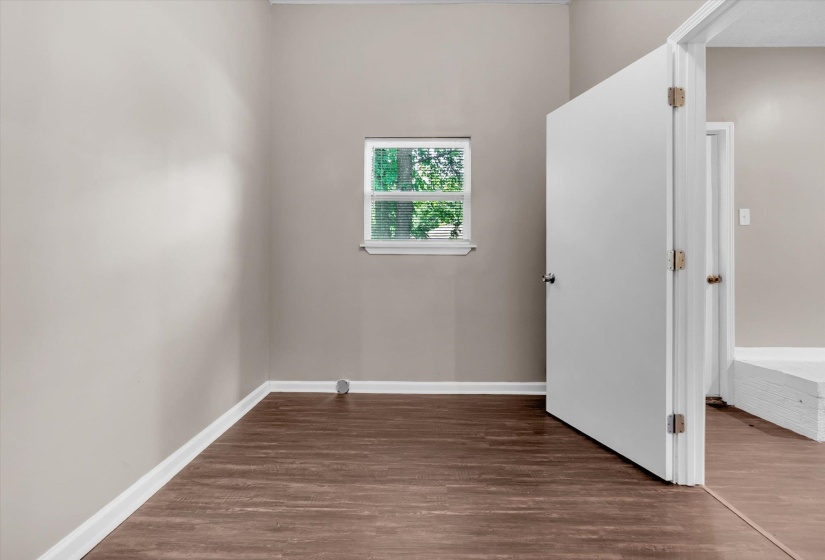 Interior room featuring neutral wall paint, wood-finish flooring, and white baseboards