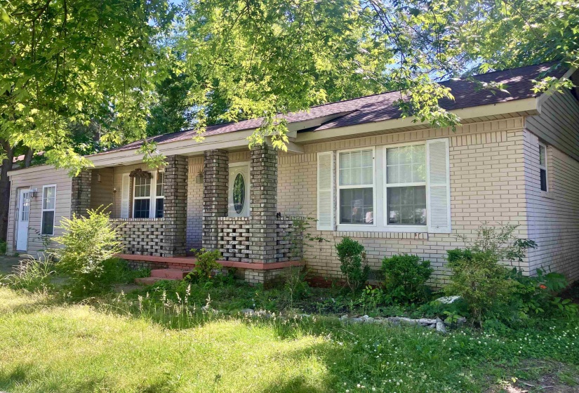 Brick and siding exterior featuring a covered front porch with brick column accents and a white entry door with an oval glass insert