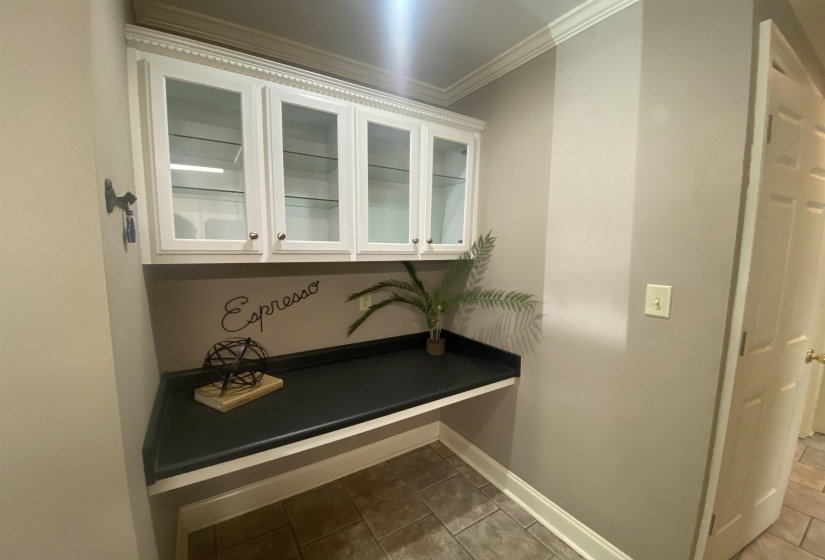 Built-in cabinetry with glass-front upper doors, a dark countertop, and crown molding