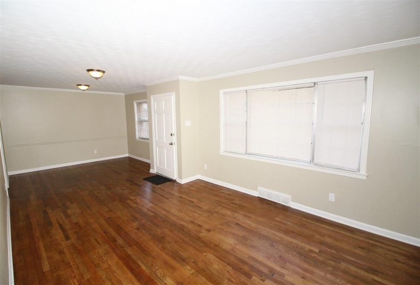 Hardwood flooring extends throughout the expansive room with neutral wall tones