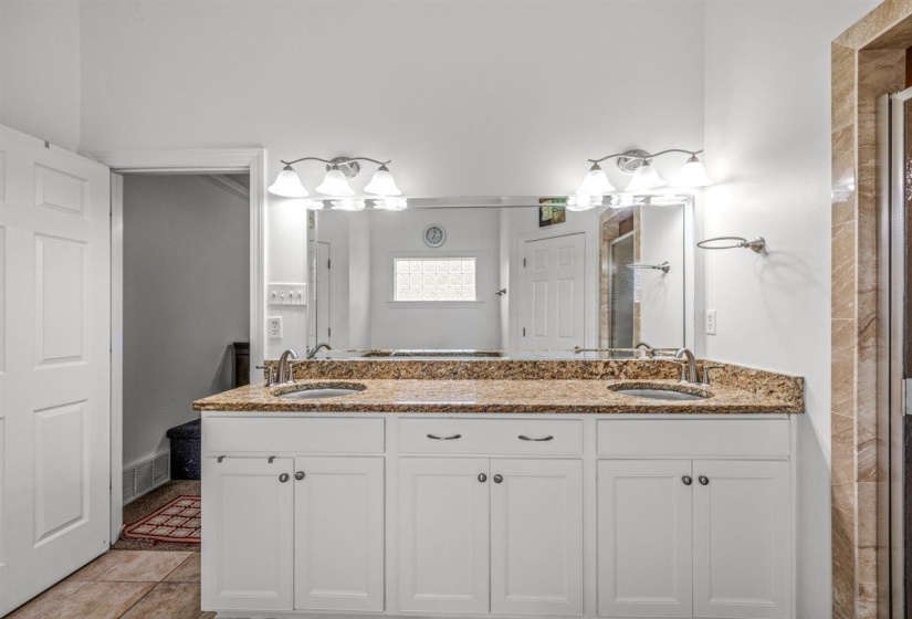 Bathroom featuring a double vanity with a stone countertop, dual undermount sinks, and white cabinetry