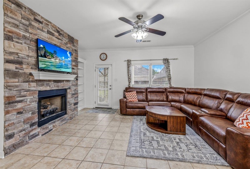 Living area with a stacked stone fireplace, a crisp white mantel, and built-in shelving