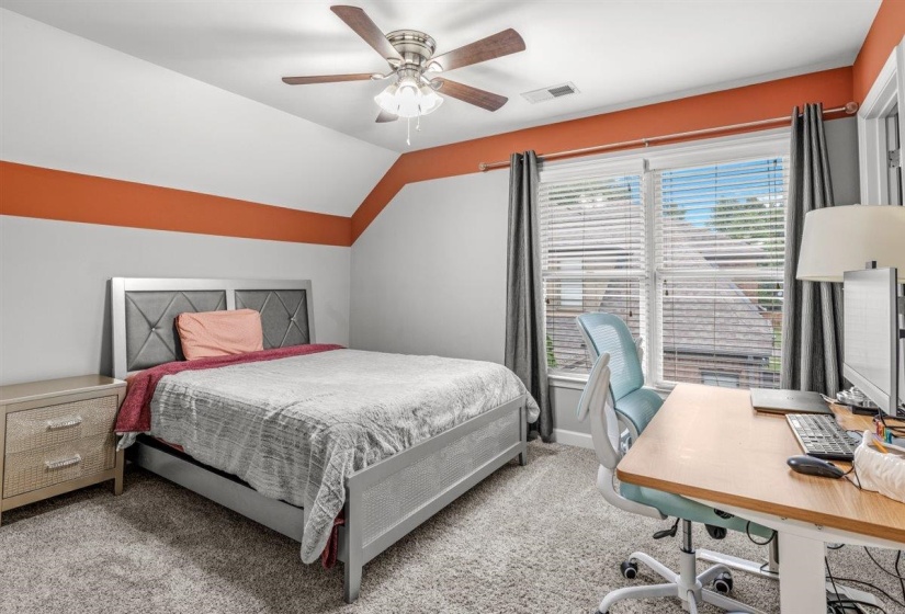 Carpeted bedroom featuring a sloped ceiling with a ceiling fan