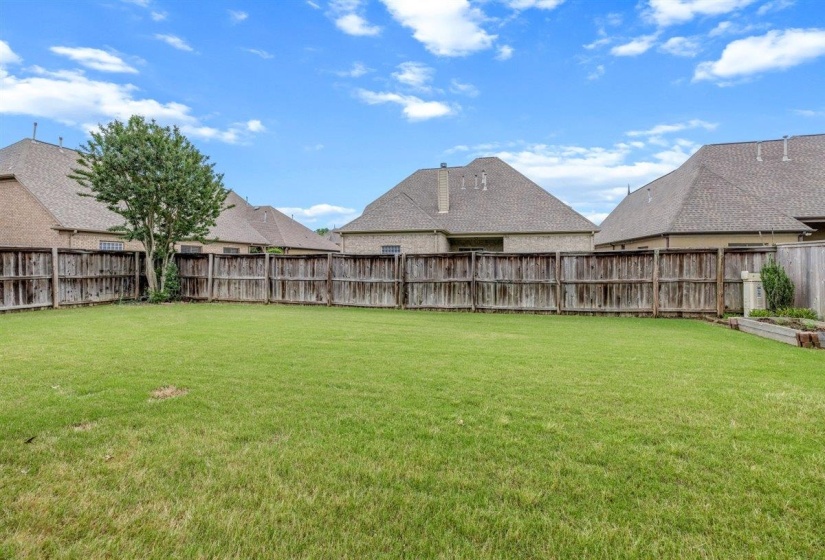 Expansive, level green lawn with a full privacy fence