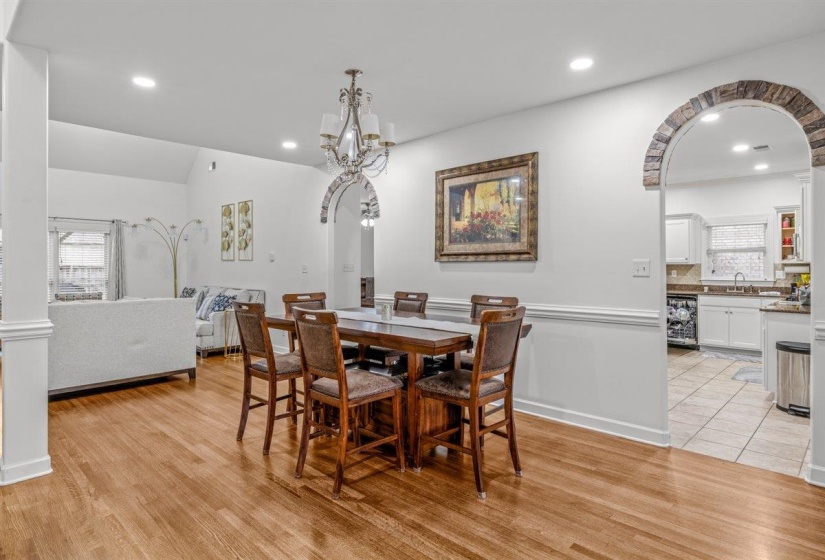 Open-concept living area with wood-finish flooring, white walls, and decorative stone archways