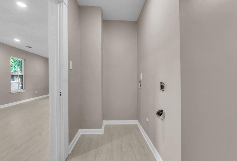 Dedicated utility space featuring light wood-finish flooring and neutral wall tones